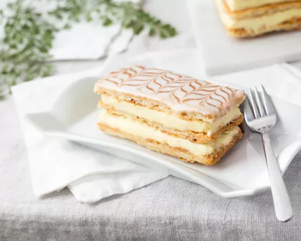 Mille Feuille cake on a plate with a fork and napkins