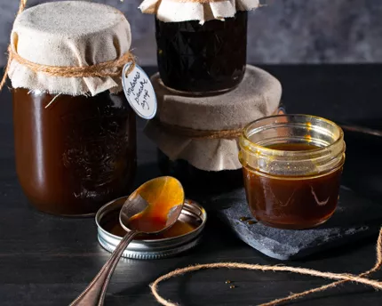 Four jars of molasses pancake syrup, one open with a spoon beside